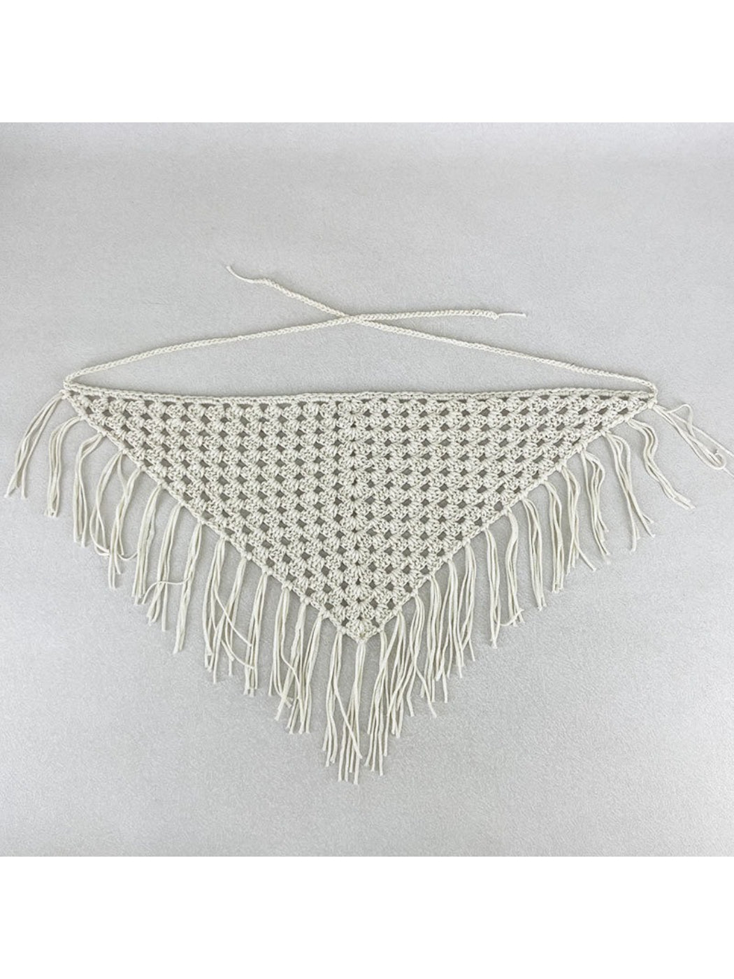 Flat lay of the crochet bandana with tassels spread out on a white background