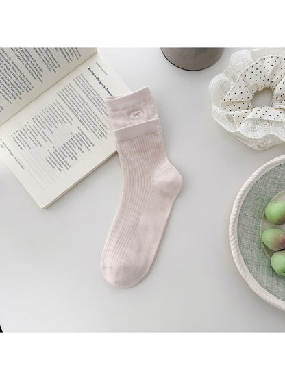 Pair of Rufia embroidered mesh mid-calf socks laid out with embroidery details visible