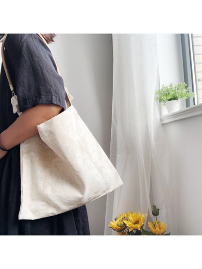 Ivory patterned hobo bag styled with casual outfit on a wooden surface
