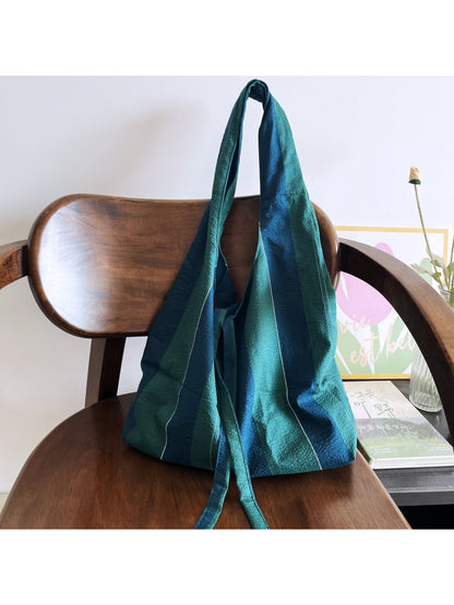 Side view of Cosbai green stripe slouch shoulder bag showing its relaxed shape