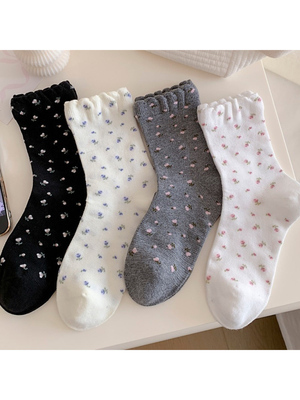Stacked Rufia Tiny Blossom socks in multiple pastel shades with frill edges visible