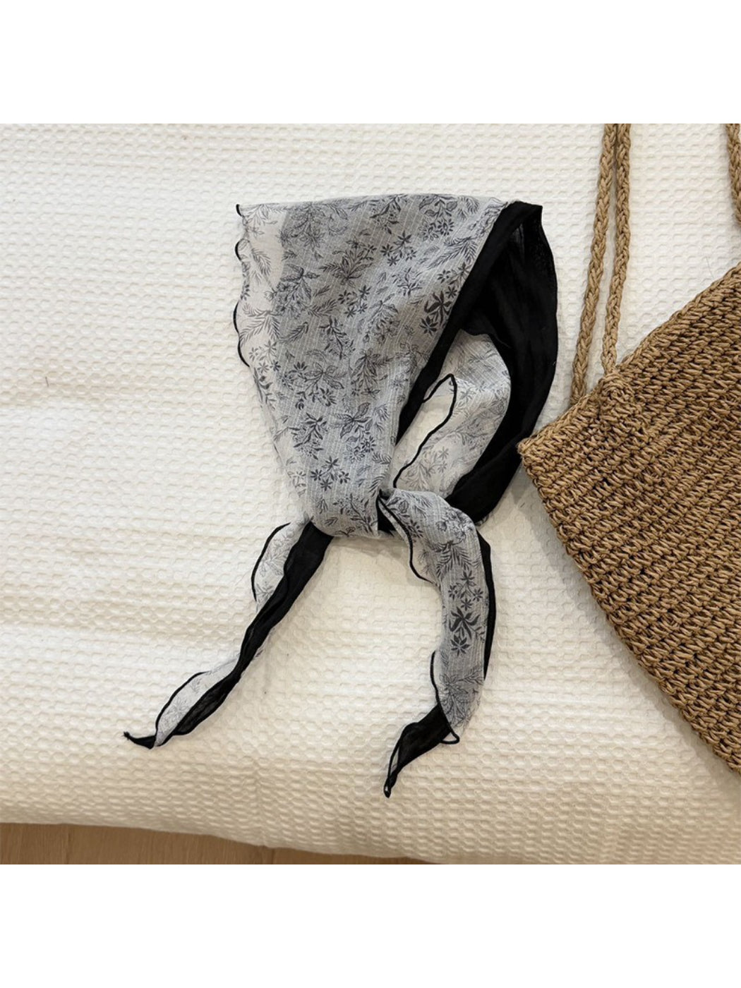 Lightweight botanical triangle scarf draped over a wooden hanger