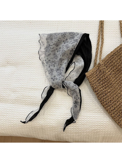 Lightweight botanical triangle scarf draped over a wooden hanger