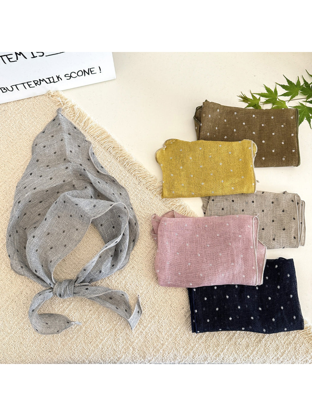 Soft textured head scarf with black and white polka dot pattern folded on a white background