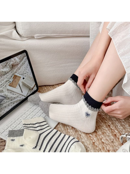 White ankle socks with pink bows folded neatly on a wooden surface