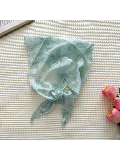 Triangle scarf with floral embroidery gently tied in a knot on a mannequin