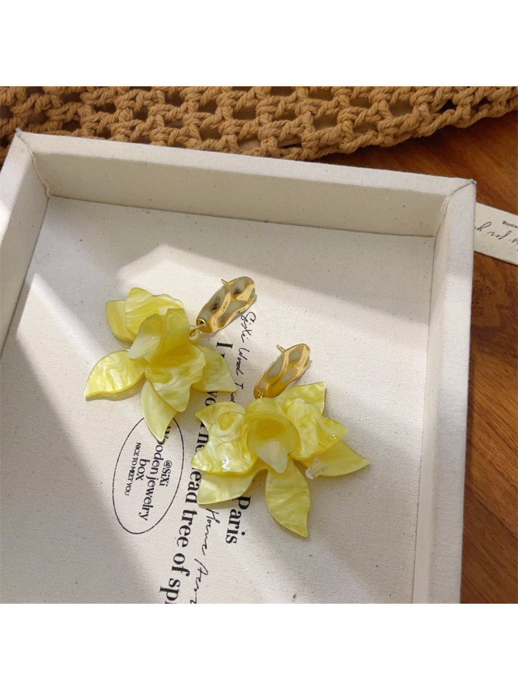 Pair of Earwish floral drop earrings placed on a textured surface