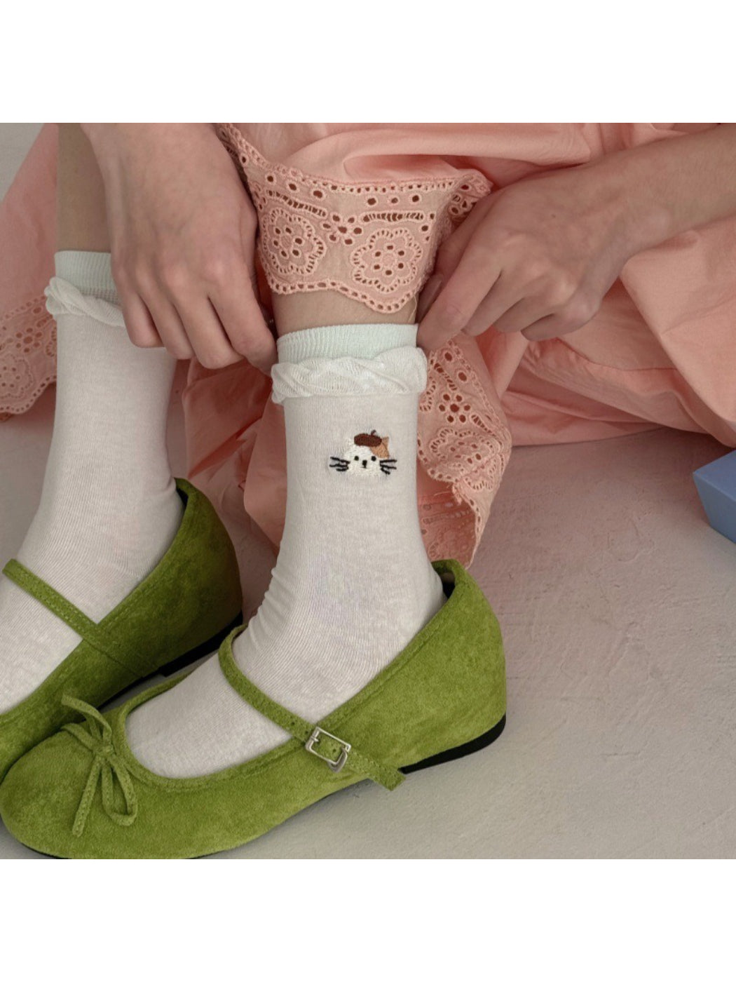 Pair of Rufia twisted cuff socks with black cat face detail on white background