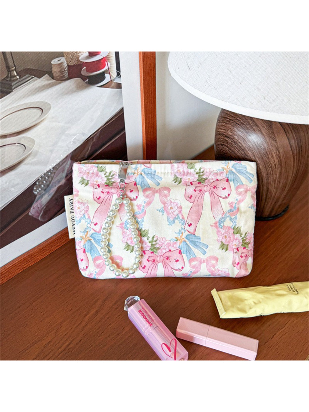 Cosbai cosmetic bag with bow detail and floral print on a plain background