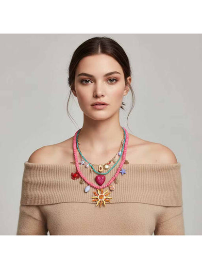 Close-up of Neckit layered charm necklace with sun and heart pendants on a model's neck
