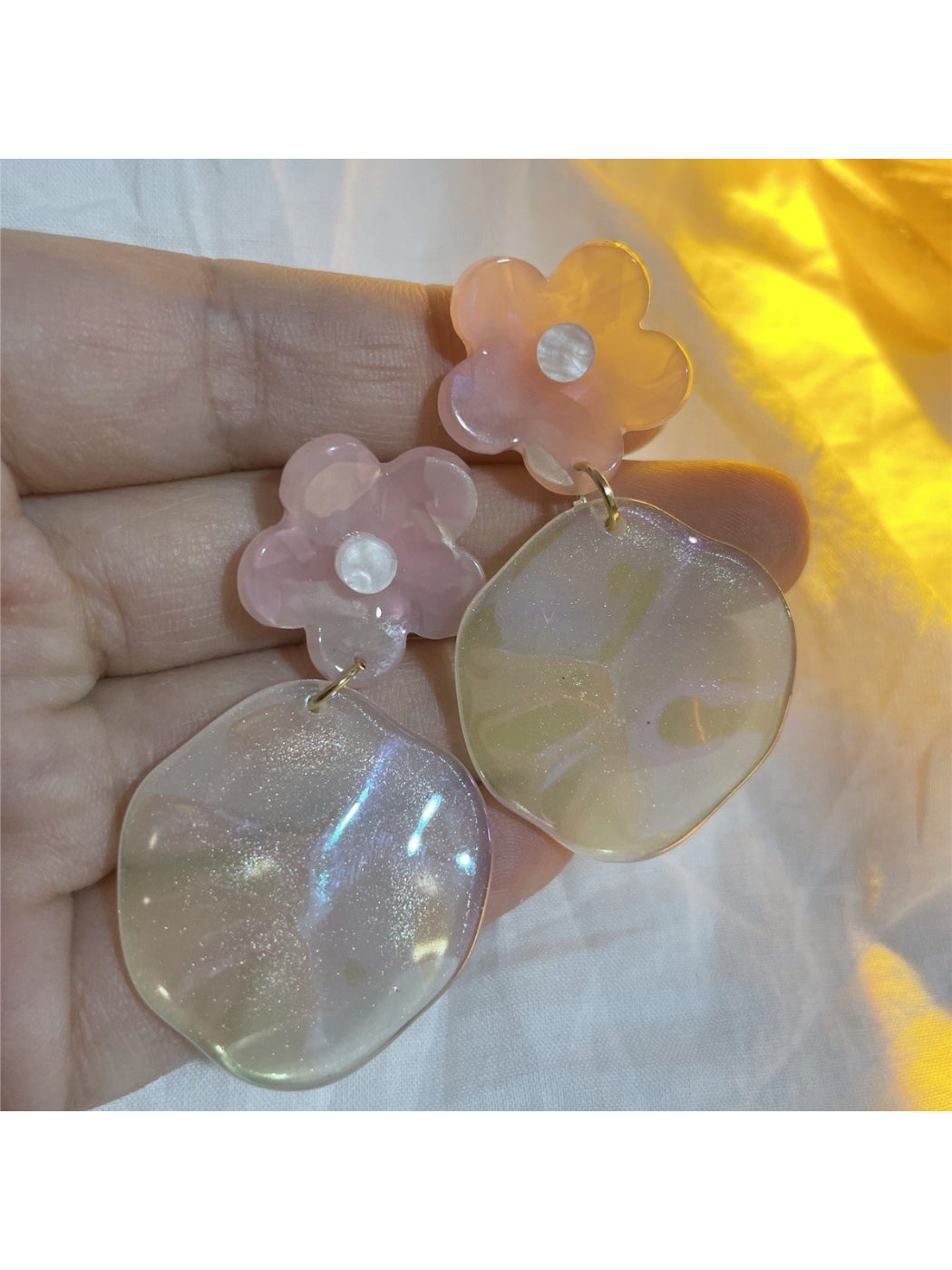 Glossy floral drop earrings with pink and white petals on a white background