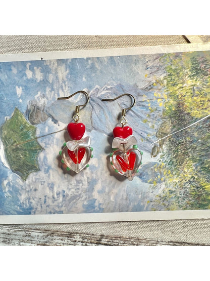 Side angle of Earwish Playful Apple Heart Earrings highlighting the gold-tone edges