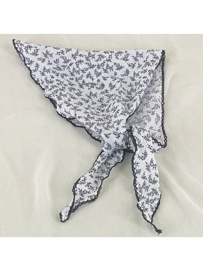 Close-up of Scarvii bandana headscarf fabric with small pink and white flowers on light background