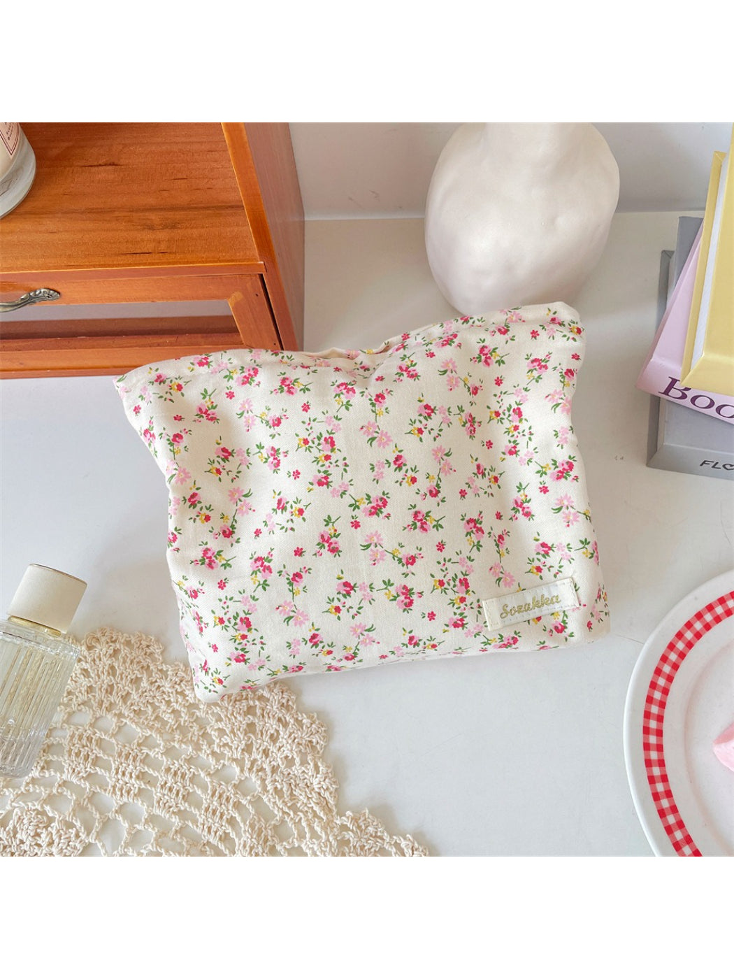 Cosbai cosmetic pouch with floral print placed on white surface with lighting