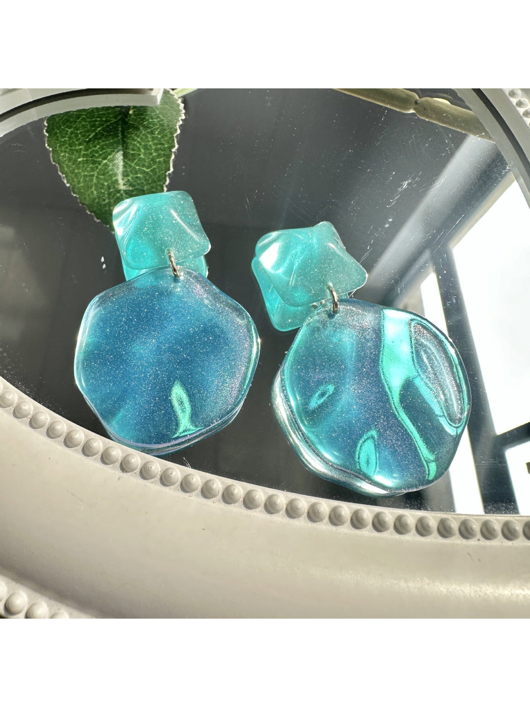 Close-up of ocean blue teardrop earrings showing smooth glossy surface