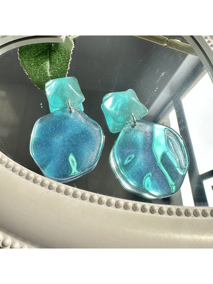 Close-up of ocean blue teardrop earrings showing smooth glossy surface