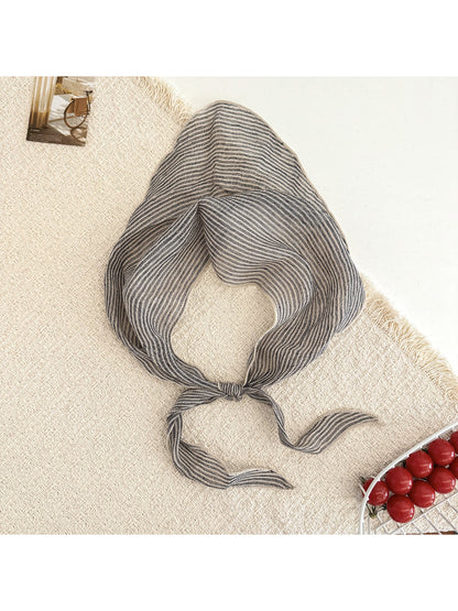 Folded Scarvii plaid triangle scarf highlighting soft fabric texture and neutral color palette