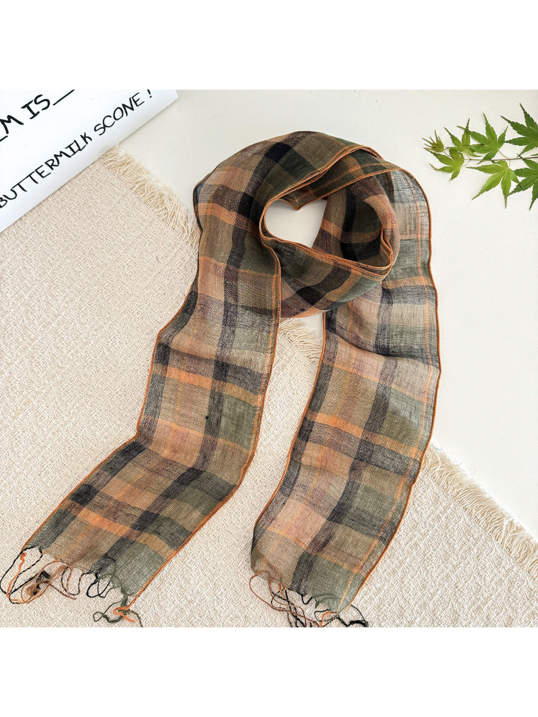 Soft check pattern long skinny scarf draped over a chair highlighting fabric flow