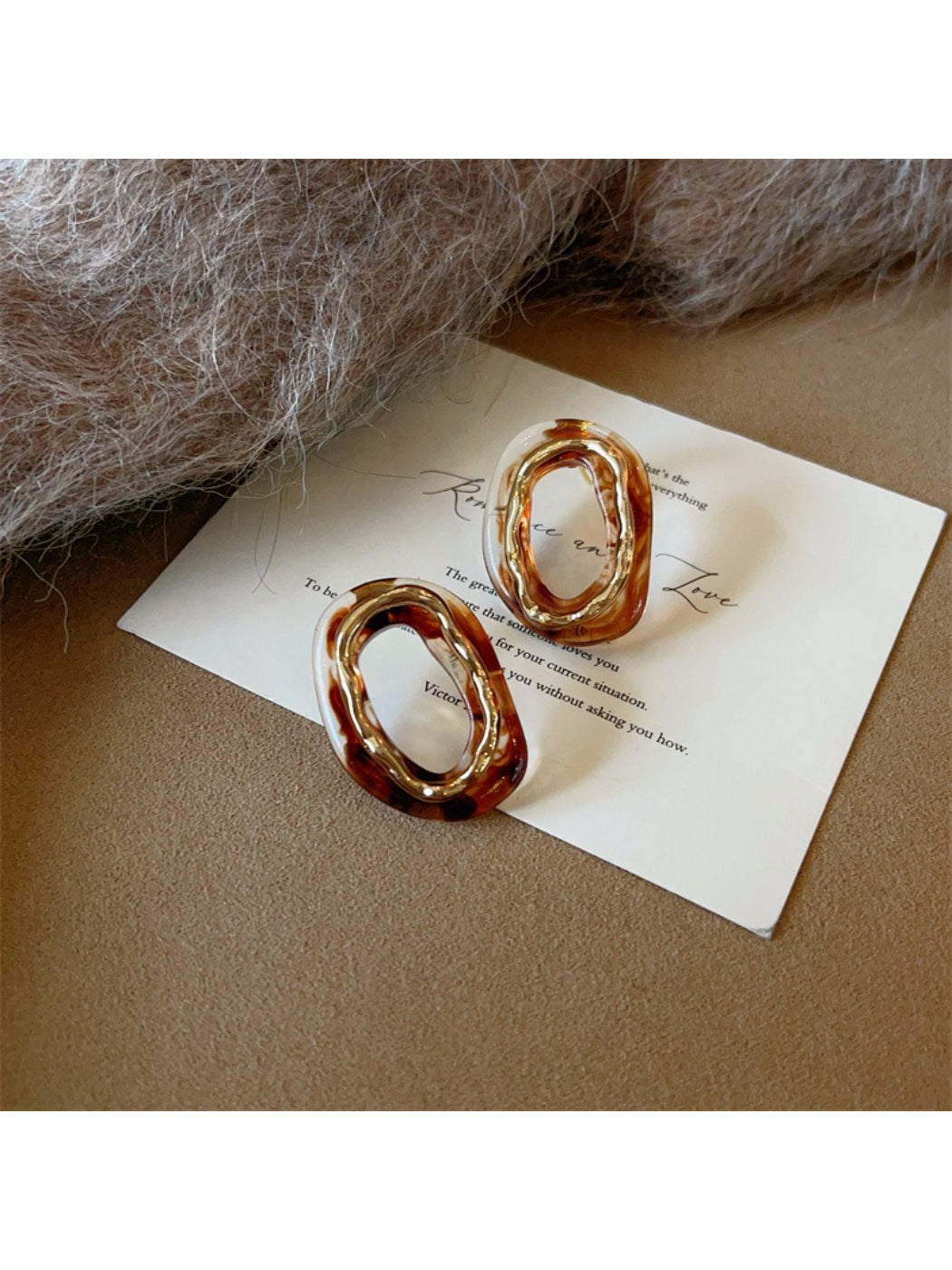 Earwish oval earrings displayed on a minimalist stand with soft lighting