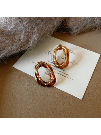 Earwish oval earrings displayed on a minimalist stand with soft lighting