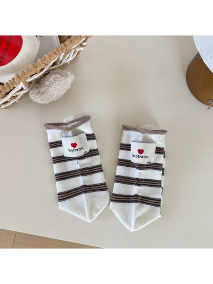 Rufia neutral crew socks paired with casual sneakers on a wooden floor