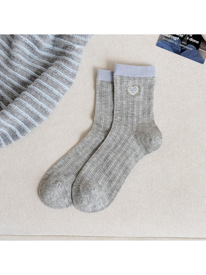 Soft pastel socks with heart details folded on a wooden surface