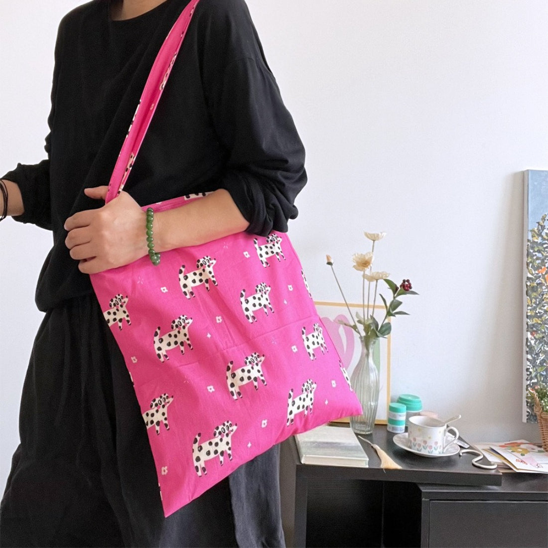Flat lay of pink puppy print tote bag with accessories inside