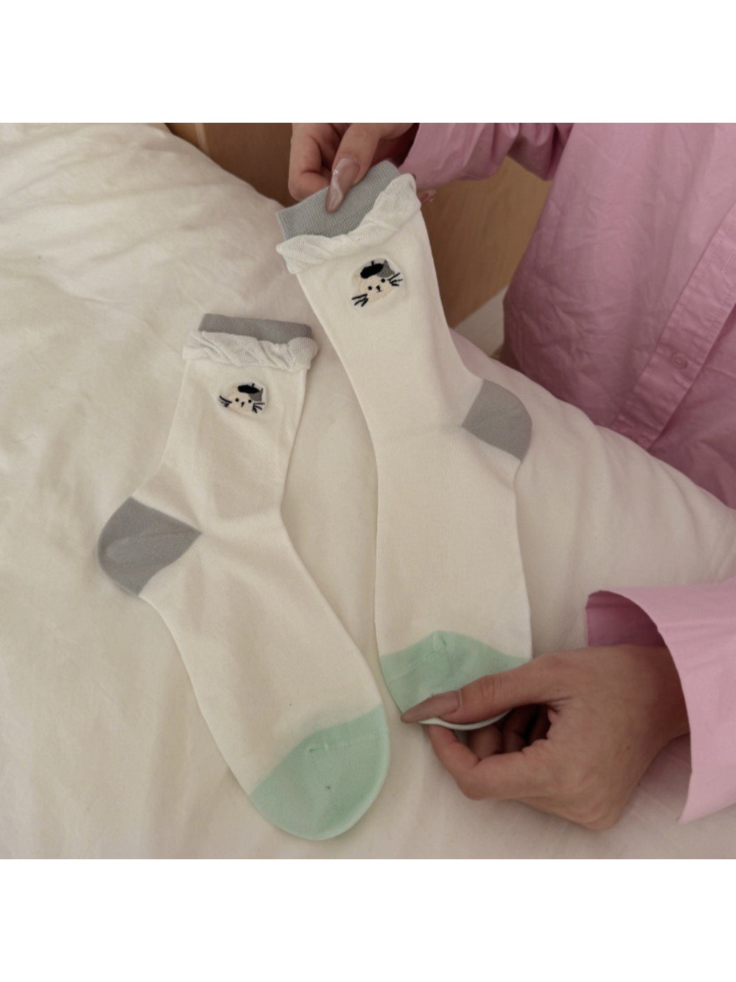 Top view of twisted cuff socks with black cat detail on white fabric