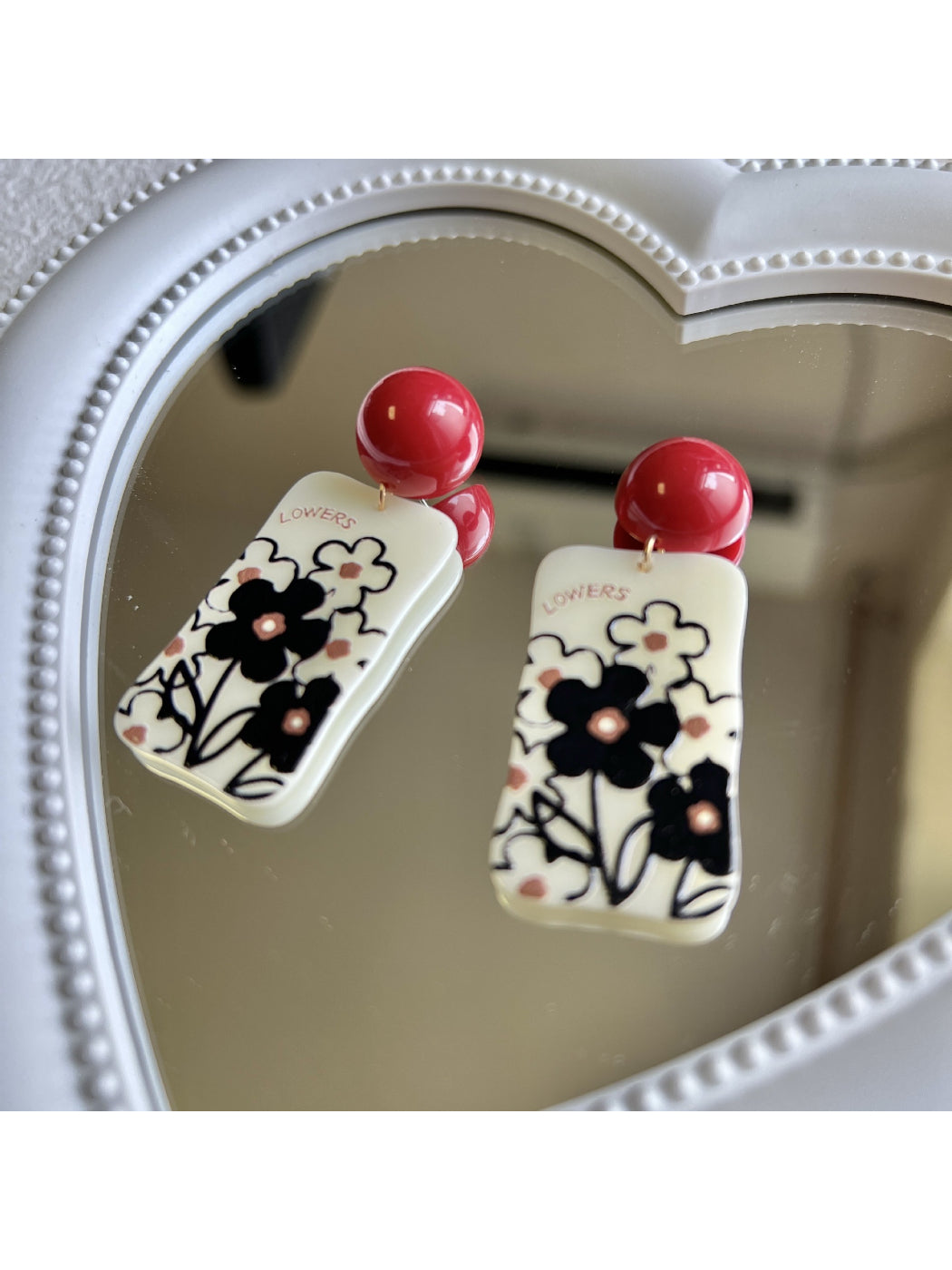 Earwish earrings displayed on a white background highlighting the drop style and floral graphic