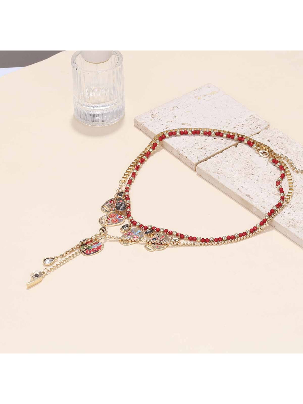 Neckit layered necklace with skull charm and red beads shown against a neutral background