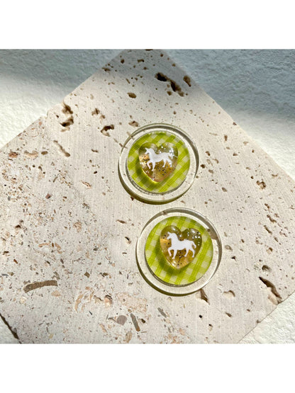 Green check horse earrings displayed on a jewelry stand