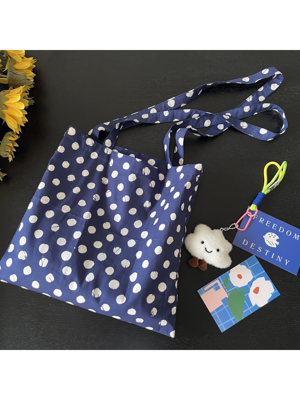Cosbai navy polka dot tote bag hanging from shoulder with tan straps