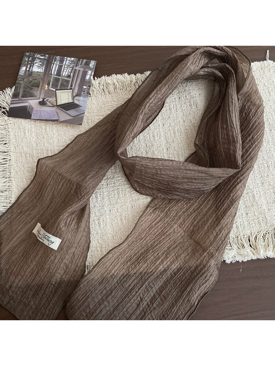 Model wearing a pleated neck scarf styled loosely around the neck with a white blouse