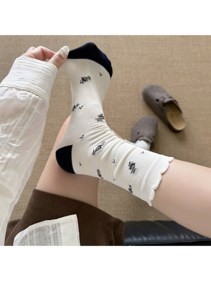 Rufia Classic Floral Knit Crew Socks displayed on wooden surface with soft light