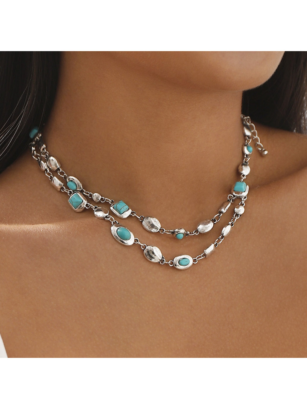 Model wearing Neckit layered gem chain necklace styled with a white top