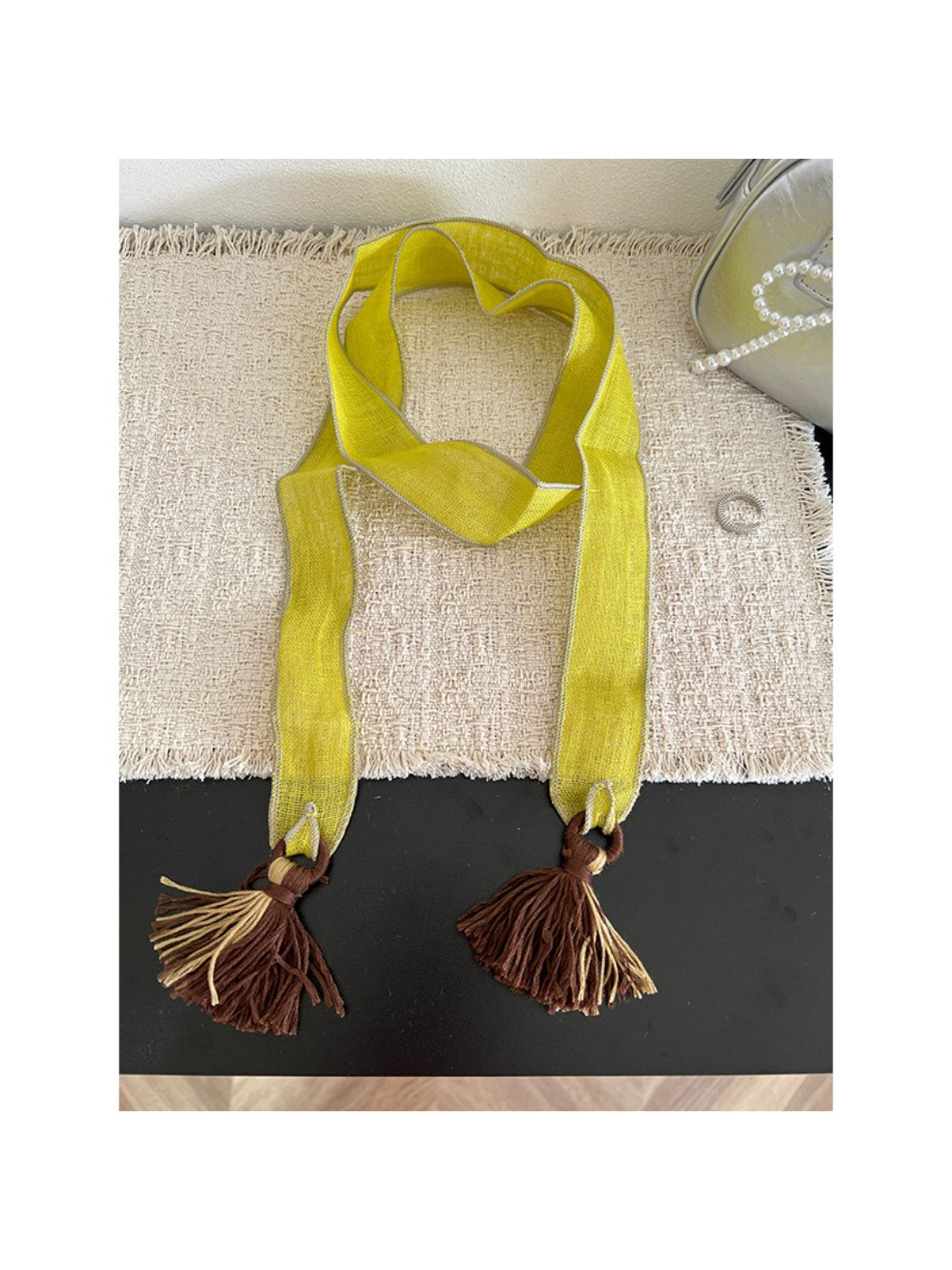 Scarvii skinny scarf with boho tassel trim displayed on wooden surface