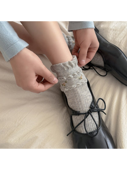 Close-up of floral embroidery on Rufia ribbed crew socks in beige