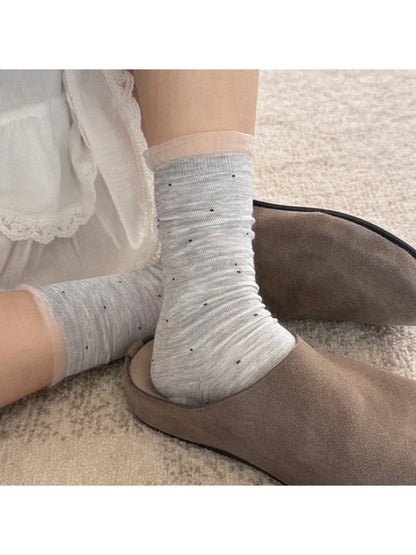 Pair of Rufia soft polka mesh socks folded neatly on a wooden surface