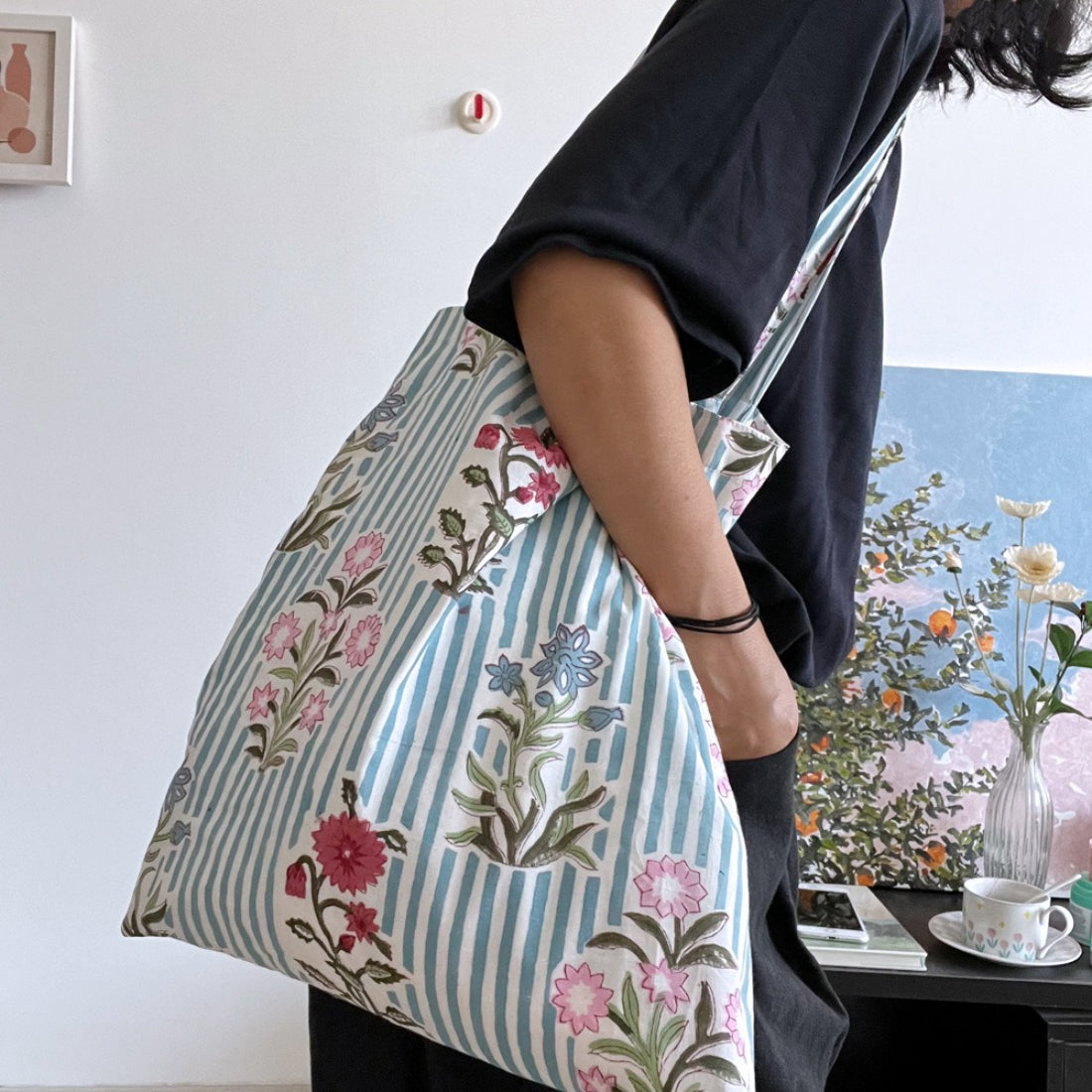 Blue stripe floral tote bag held by a model wearing casual outfit