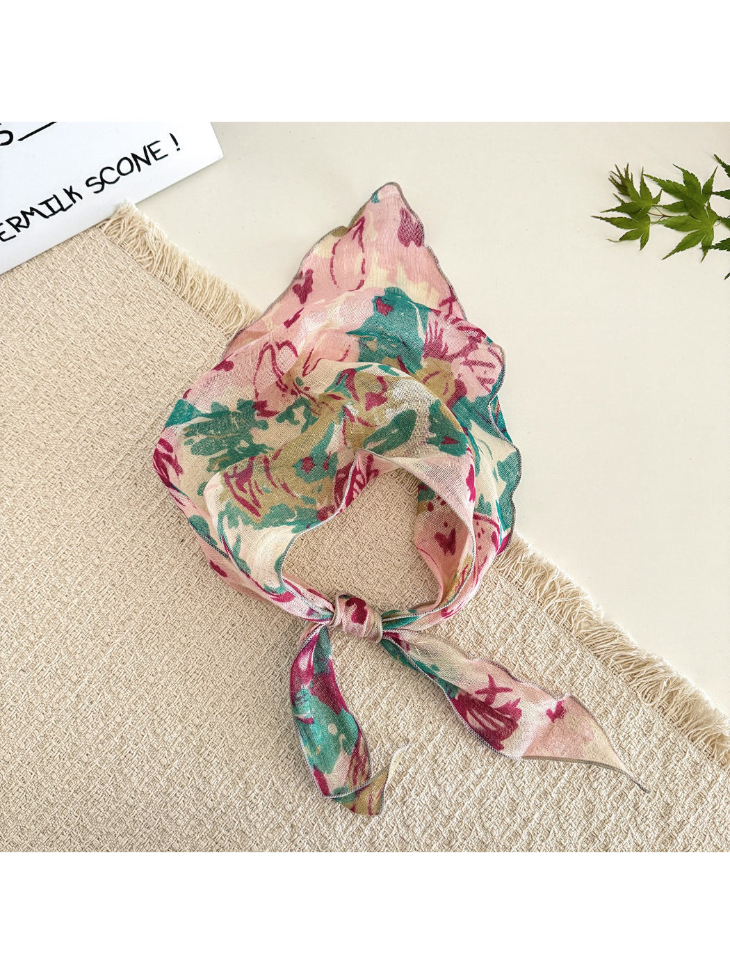 Model wearing lightweight floral triangle scarf tied around the neck with casual outfit