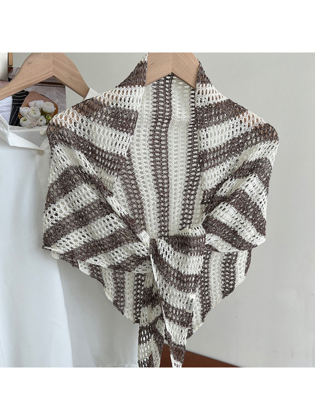 Scarvii striped triangle scarf laid out with soft natural lighting