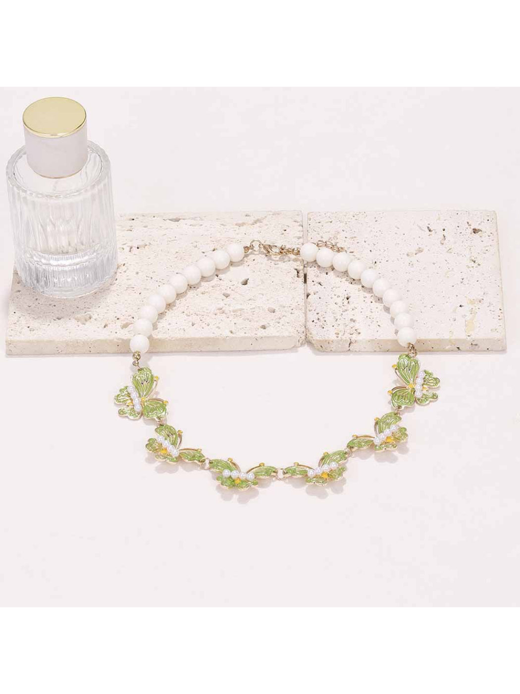 Neckit Butterfly Necklace with beaded detail shown against a soft pink background
