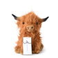 Cow plush toy sitting upright on plain background