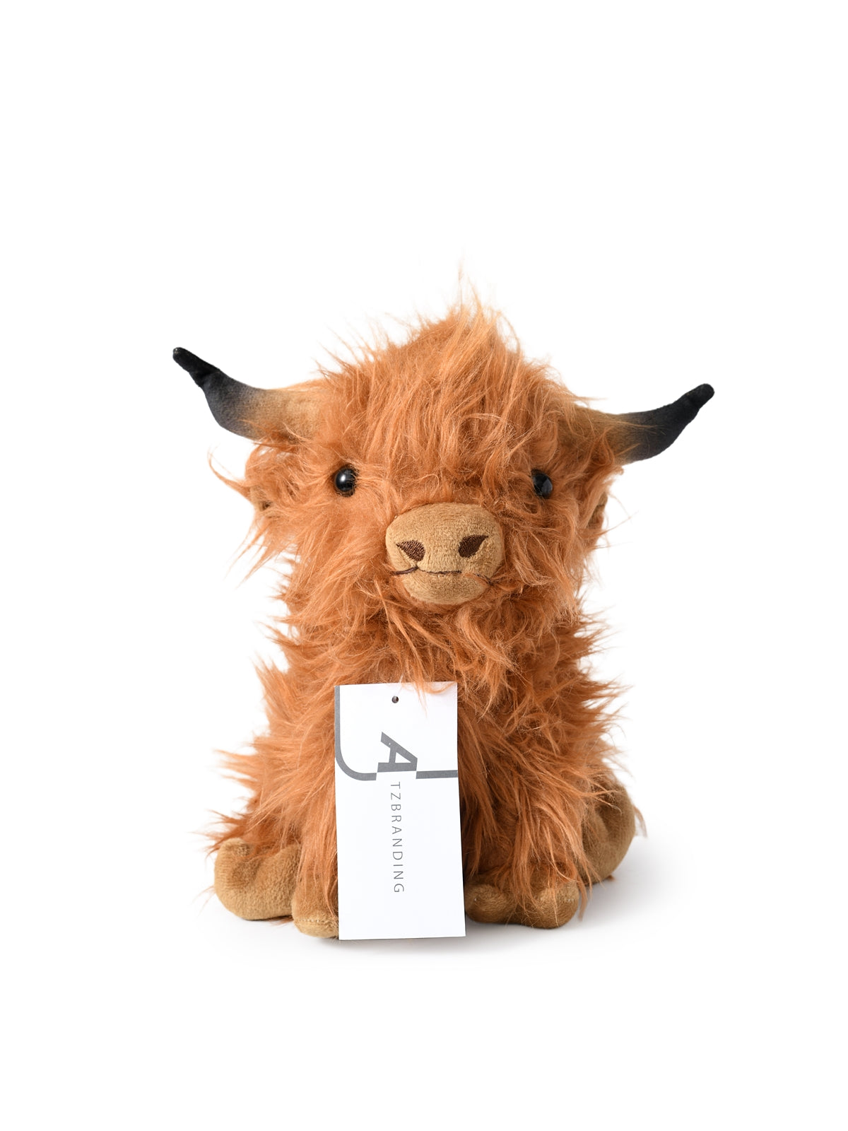 Cow plush toy sitting upright on plain background