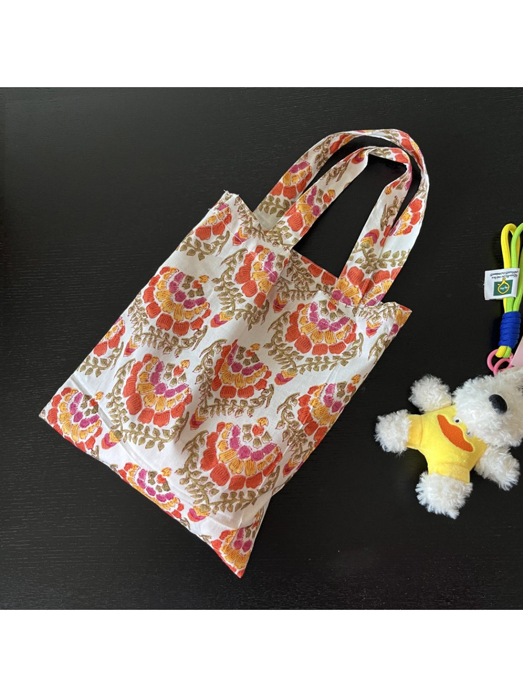 Cosbai tote bag hanging on a hook displaying full print and shape