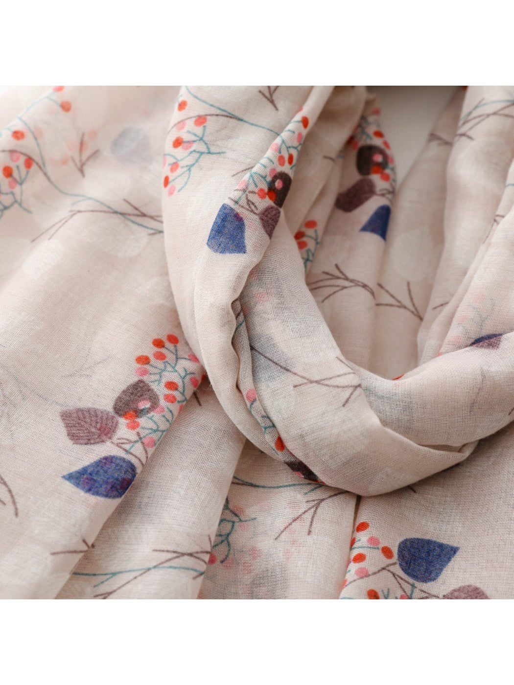 Scarf laid flat showing detailed floral and leaf motifs in soft colors