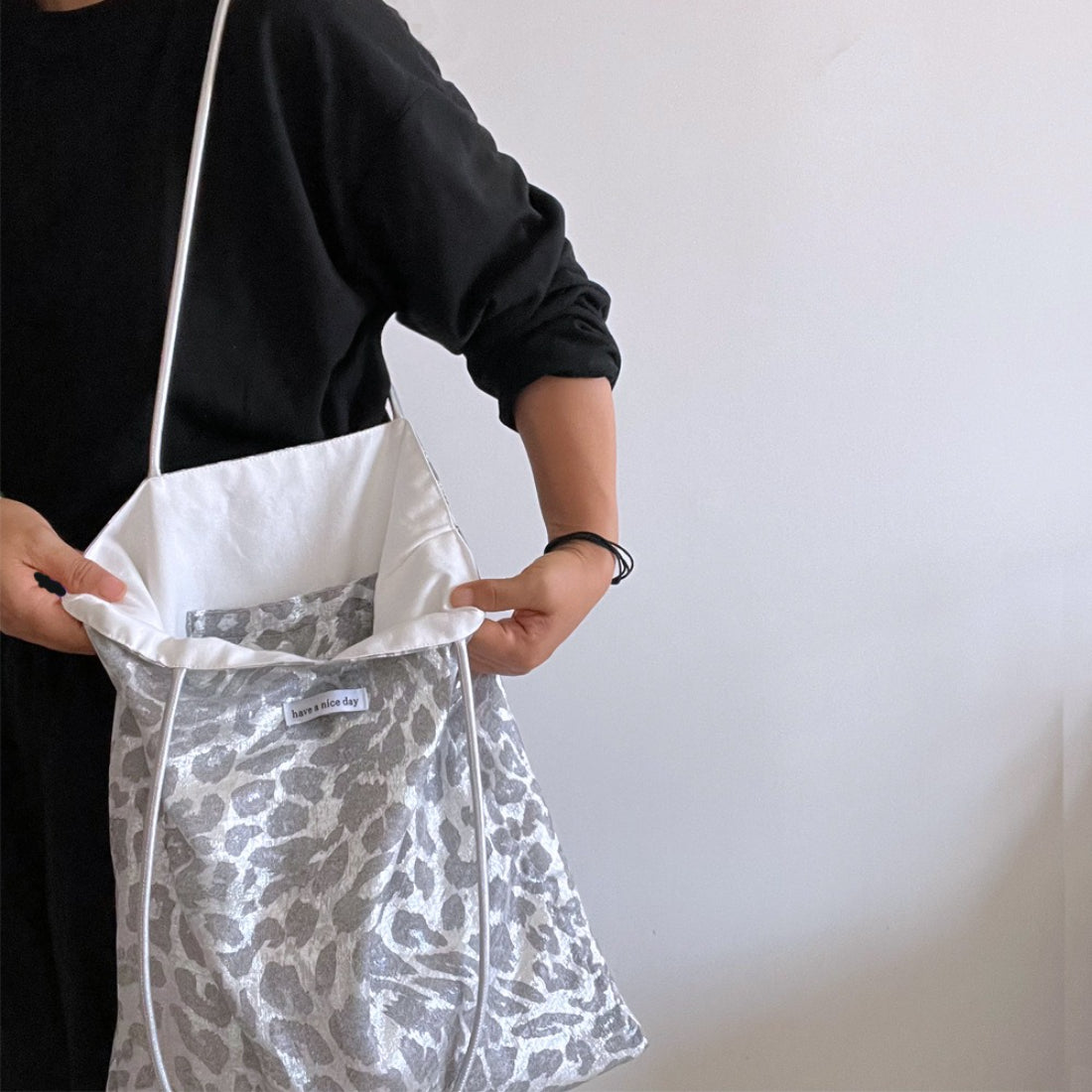 Grey leopard print tote bag hanging on a hook against white wall