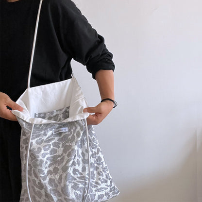 Grey leopard print tote bag hanging on a hook against white wall