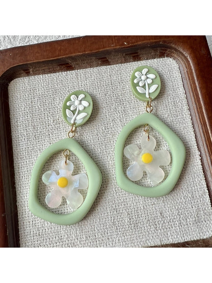 Close-up of green daisy hoop earrings with detailed petals and gold hoops