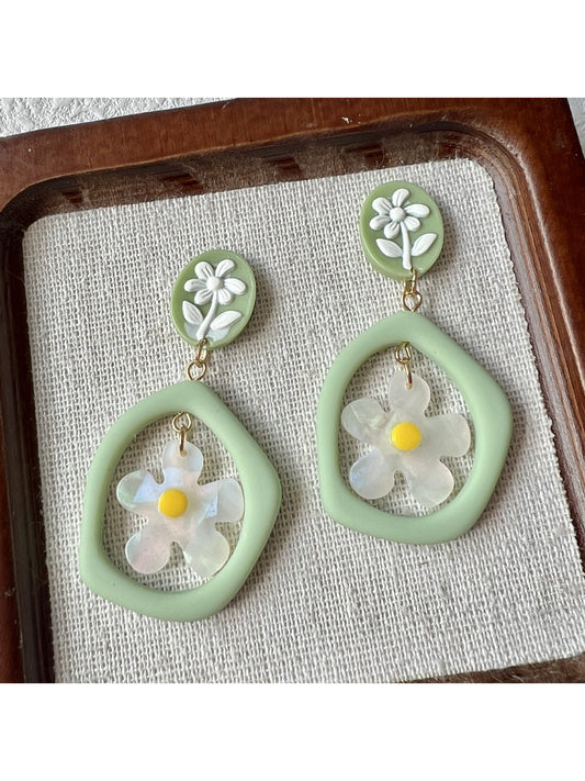 Close-up of green daisy hoop earrings with detailed petals and gold hoops